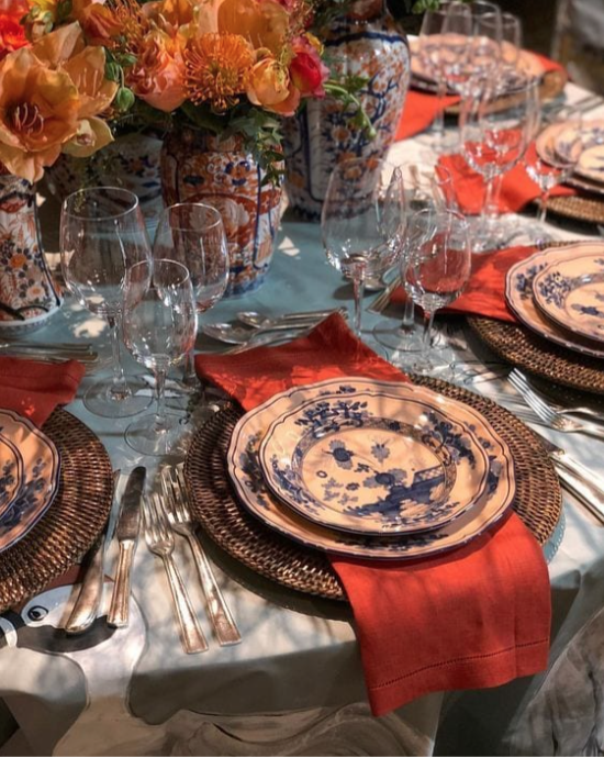 Jewel-toned Thanksgiving table featuring layered place settings, magnolia leaves, and polished silver.*